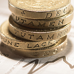 British Currency: Stacked pound coins on financial graphs, close-up